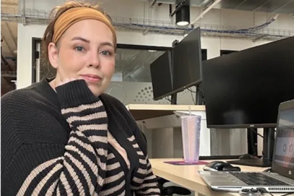 A woman in a yellow sweater typing on her laptop.