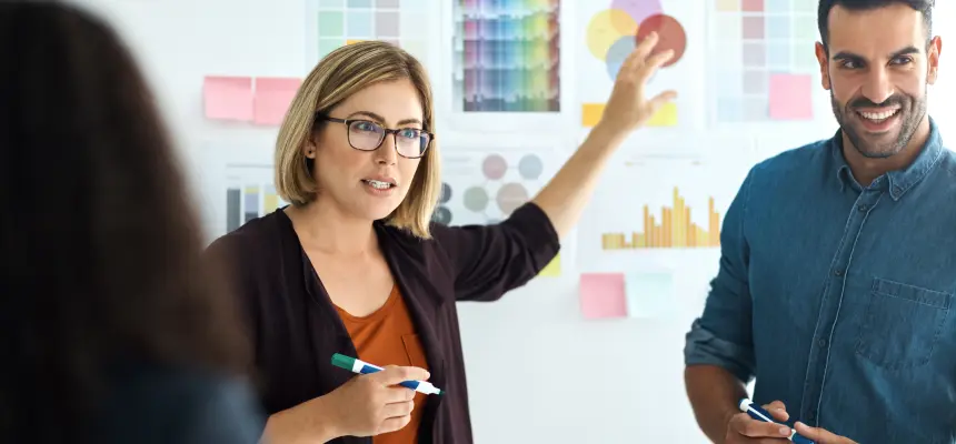 A man and woman standing in front of a whiteboard, discussing a presentation.