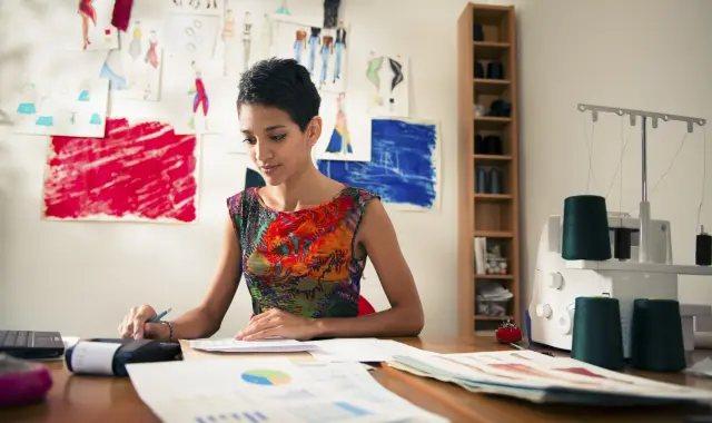 A woman sitting at a desk, writing on a piece of paper.