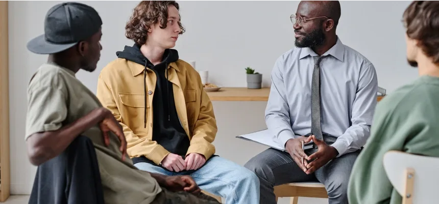 A group of men engaged in conversation while seated in a circle, fostering discussion and camaraderie among them.