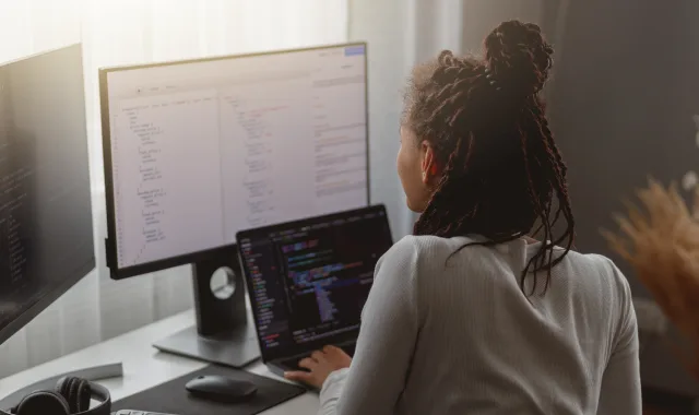 A woman sitting at a desk with two computer screens.