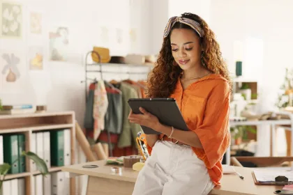 Female professional using a tablet while seated at a desk.