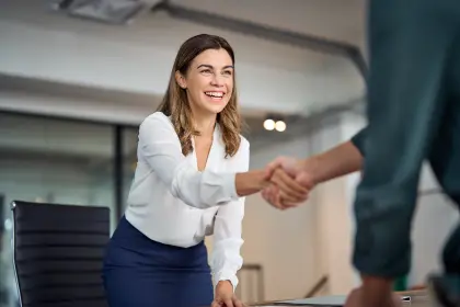 A woman and a man shaking hands in an office.