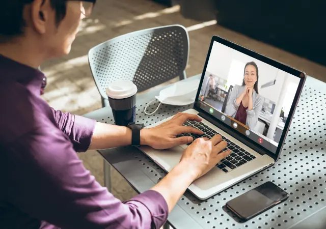 A man video chatting on laptop with someone, smiling and engaged in conversation.