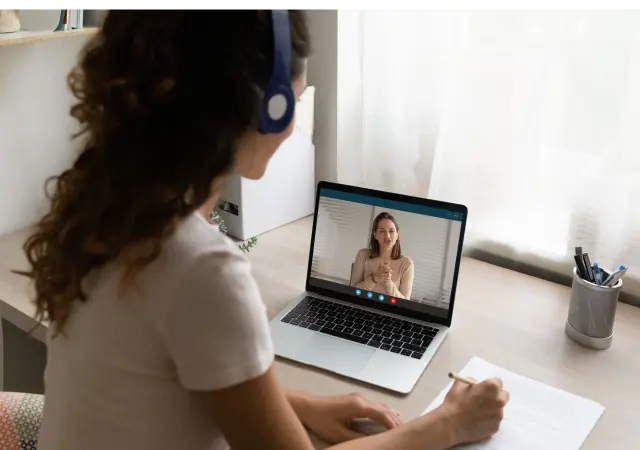 Woman sitting at desk with laptop, engaged in video call.