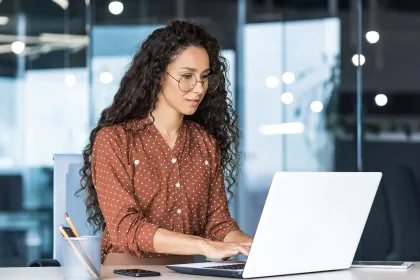 A woman wearing glasses typing on a laptop.