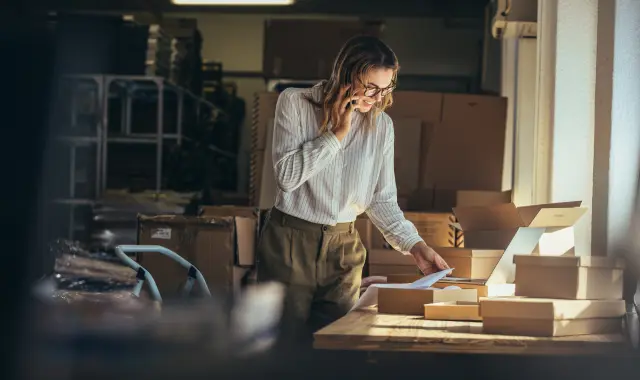 Female standing near desk with boxes.