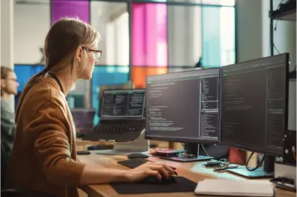 Woman typing on computer in office setting.