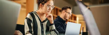 Diverse group of students working on computers in a library.