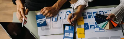 Team of individuals engaged in project work, surrounded by blue and red papers.